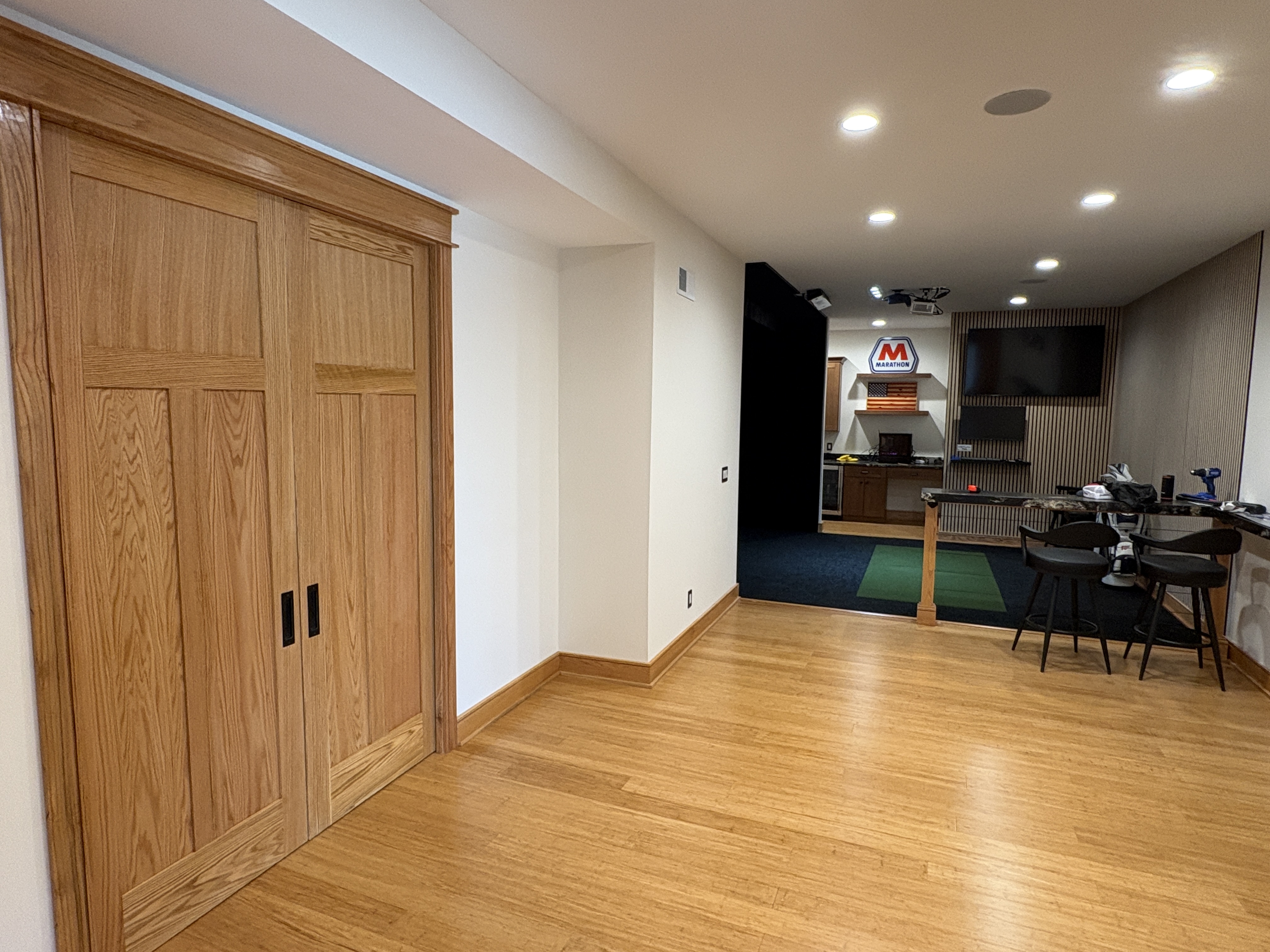 Golfers Paradise basement — oak craftsman barn doors with black hardware and bamboo hardwood floors by Luxe Built Louisville KY